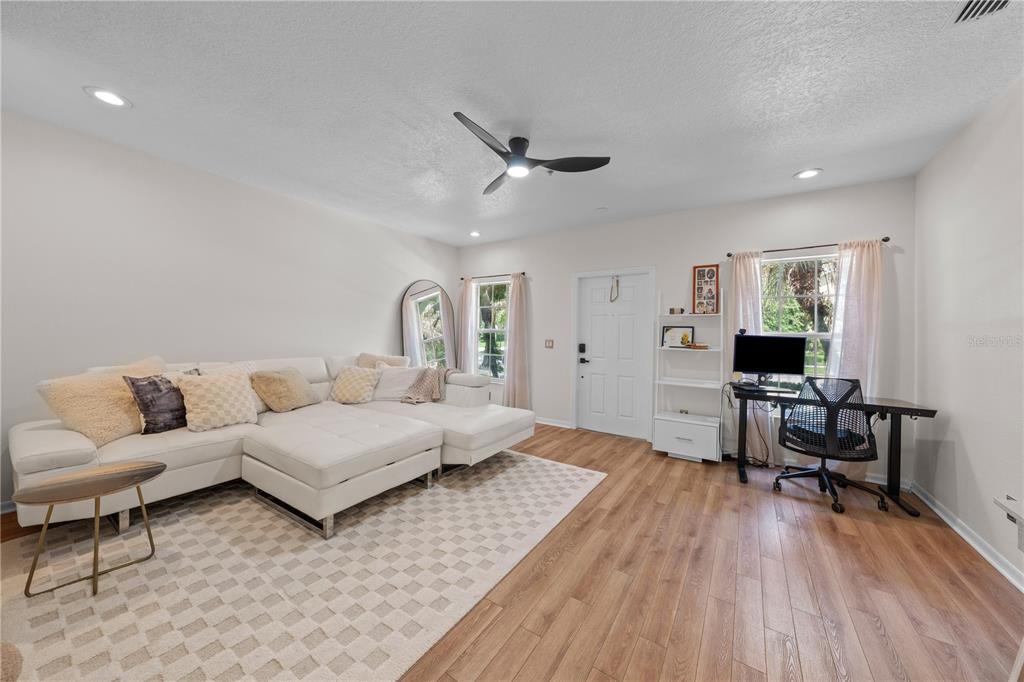A living room features a white sectional sofa, a desk, and wood-look flooring — 241 DEEPCOVE ROAD, WINTER GARDEN, FL