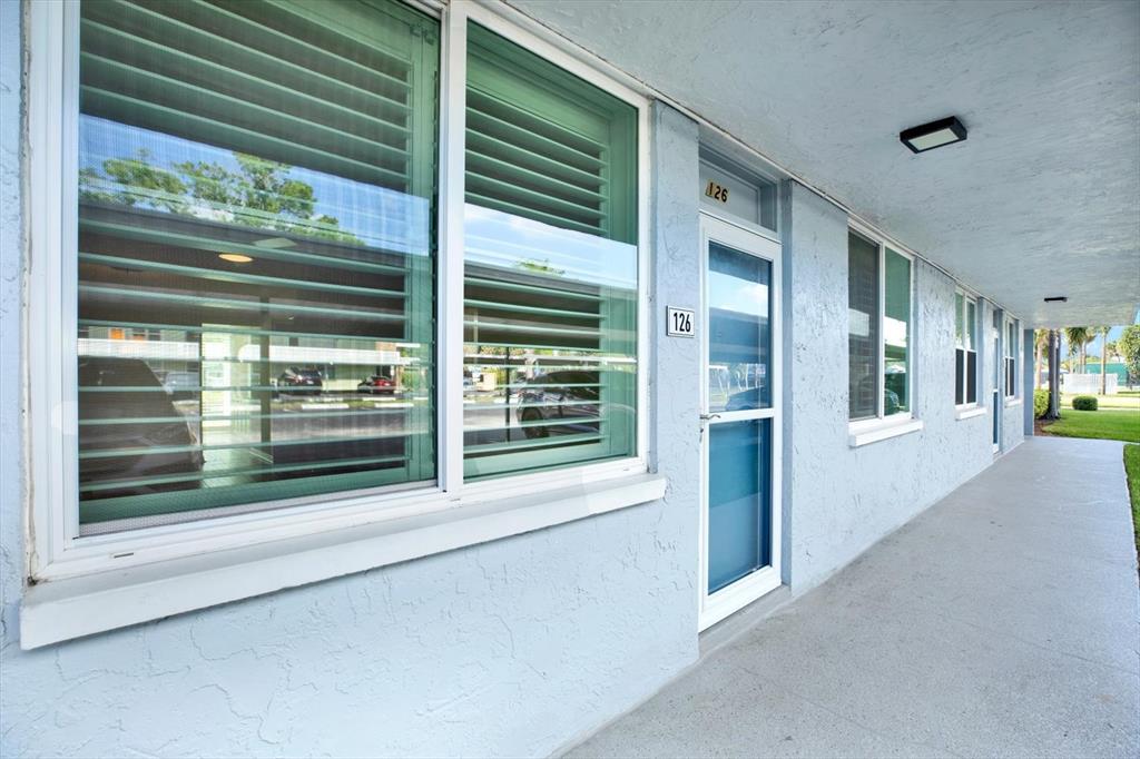 The exterior of a light blue building features a glass door and large windows — 4715 BAY STREET NE UNIT 126, ST PETERSBURG, FL