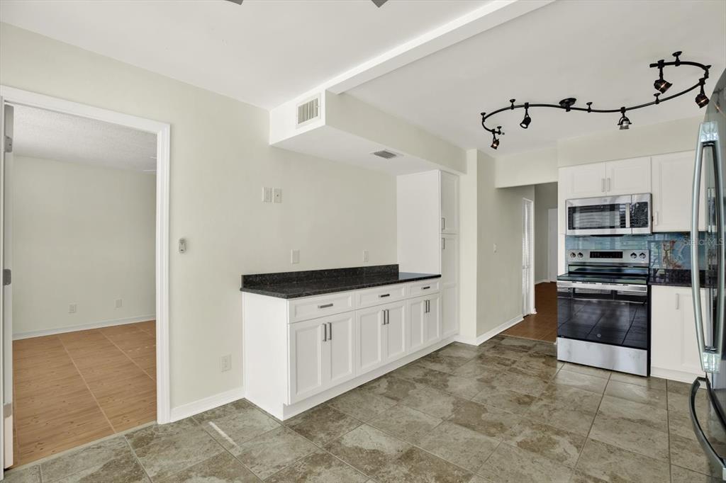 A kitchen with white cabinets, dark countertops, stainless steel appliances, and gray tile flooring — 4715 BAY STREET NE UNIT 126, ST PETERSBURG, FL