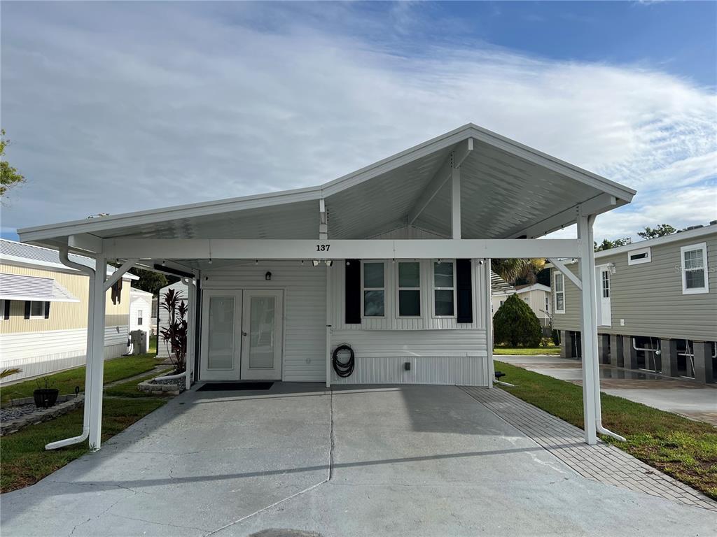 A white manufactured home features a large attached carport and a concrete driveway — 137 CITRUS RIDGE DRIVE, DAVENPORT, FL