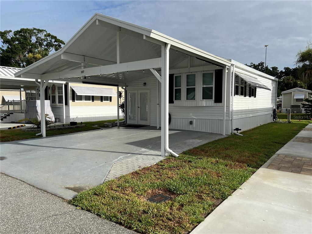 A white mobile home features a large attached carport and a concrete driveway — 137 CITRUS RIDGE DRIVE, DAVENPORT, FL