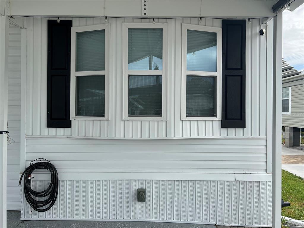 The exterior wall of a manufactured home features three windows with black shutters and siding — 137 CITRUS RIDGE DRIVE, DAVENPORT, FL