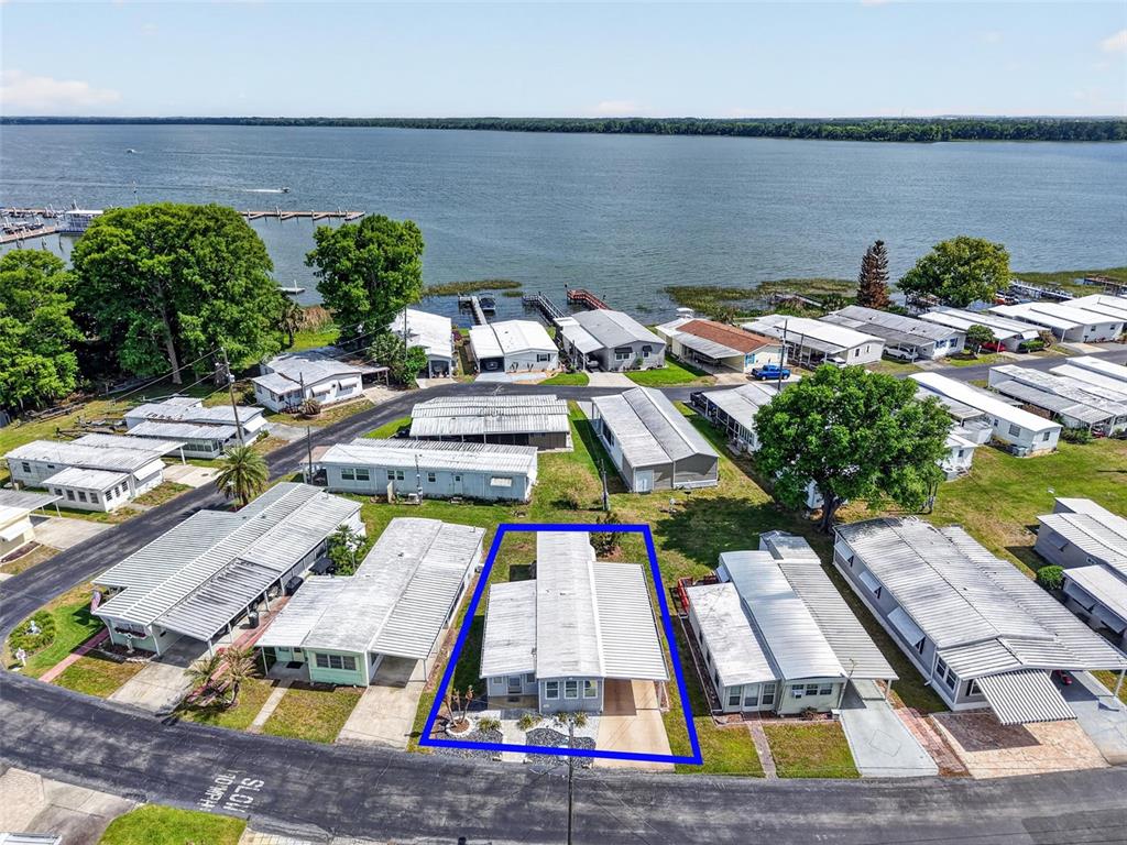 An aerial view shows a mobile home highlighted in blue within a waterfront community — 465 MARINA LANE, TAVARES, FL