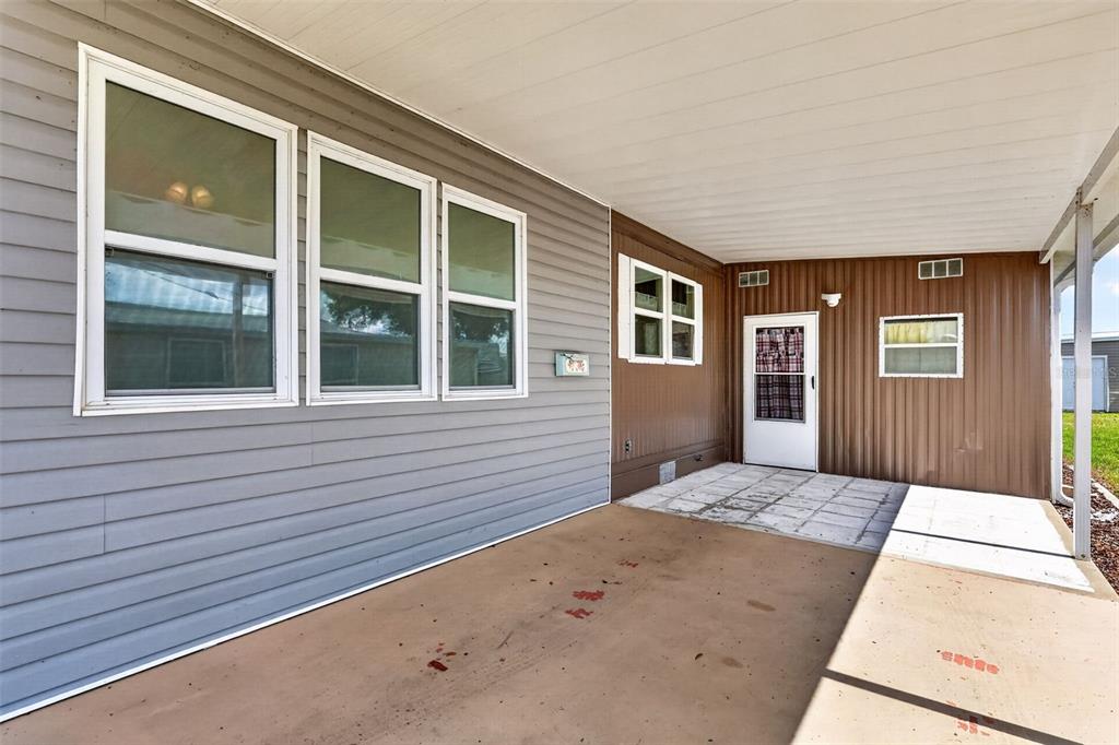A covered concrete patio features gray horizontal siding and brown vertical metal wall panels — 465 MARINA LANE, TAVARES, FL