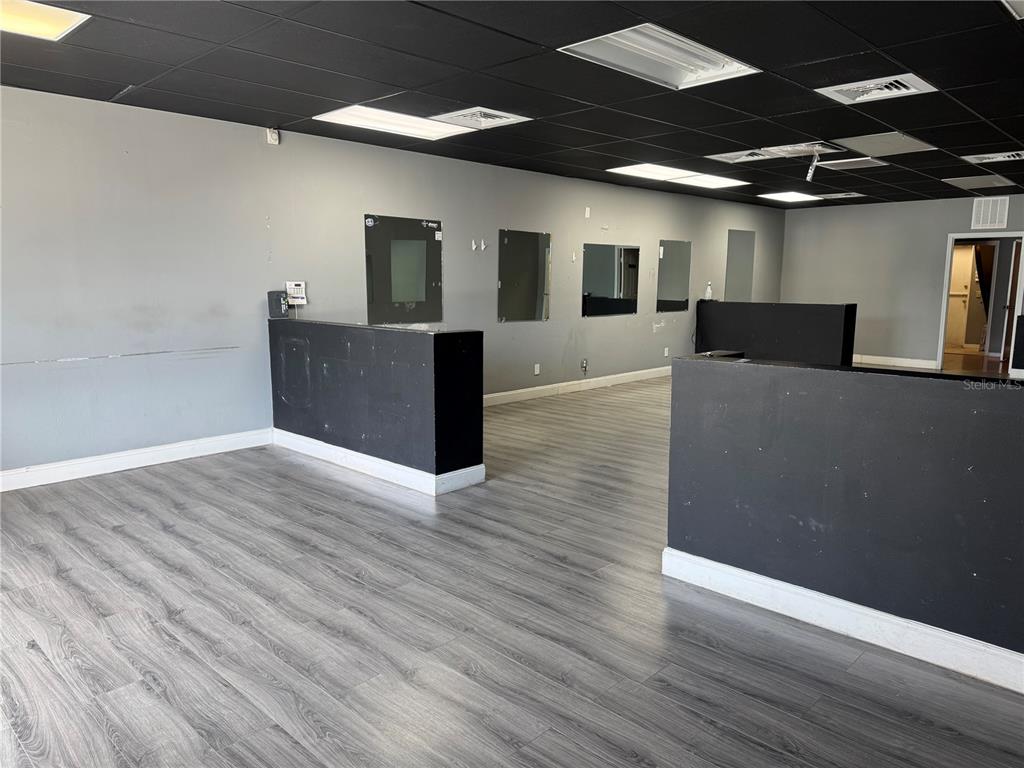 An empty commercial space features gray walls, black ceiling tiles, and wood-look laminate flooring — 302 SW TULIP BOULEVARD, PORT ST LUCIE, FL
