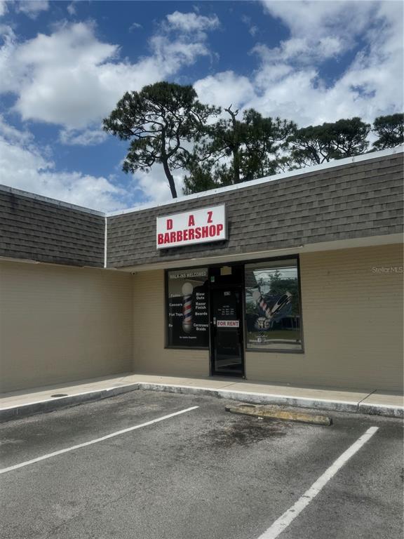 The exterior of a single-story commercial building features a Daz Barbershop sign and parking space — 302 SW TULIP BOULEVARD, PORT ST LUCIE, FL