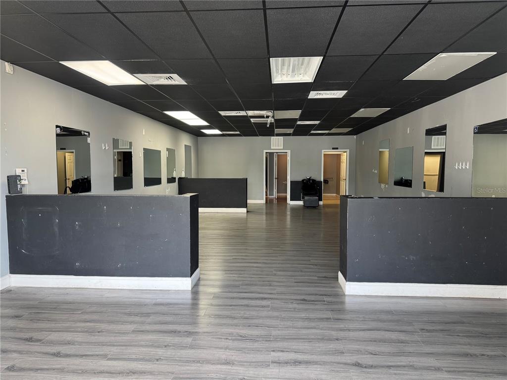 An empty commercial space with gray walls, black ceiling tiles, and wood-look flooring — 302 SW TULIP BOULEVARD, PORT ST LUCIE, FL