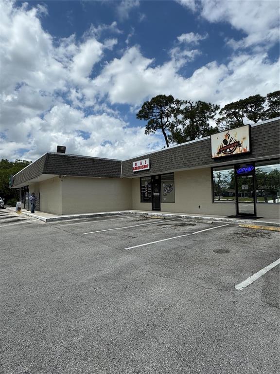 A commercial building exterior with a barbershop and a barbecue restaurant under a shingled roof — 302 SW TULIP BOULEVARD, PORT ST LUCIE, FL