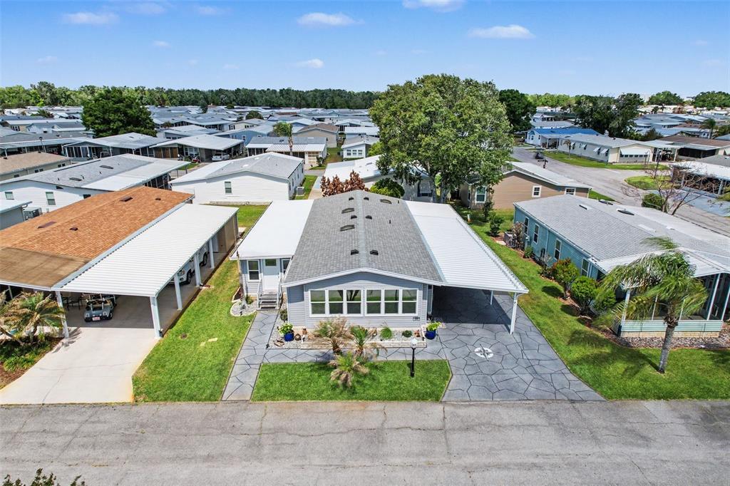 An aerial view shows a gray manufactured home with a carport and a paved driveway — 319 MELBOURN DRIVE, HAINES CITY, FL