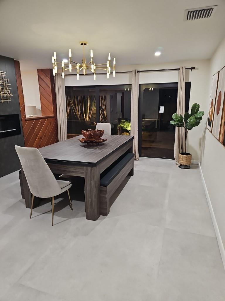 A dining room with a dark wood table, bench seating, upholstered chairs, and a modern chandelier — 7676 Overlook Drive, Lake Worth FL 33467, LAKE WORTH, FL