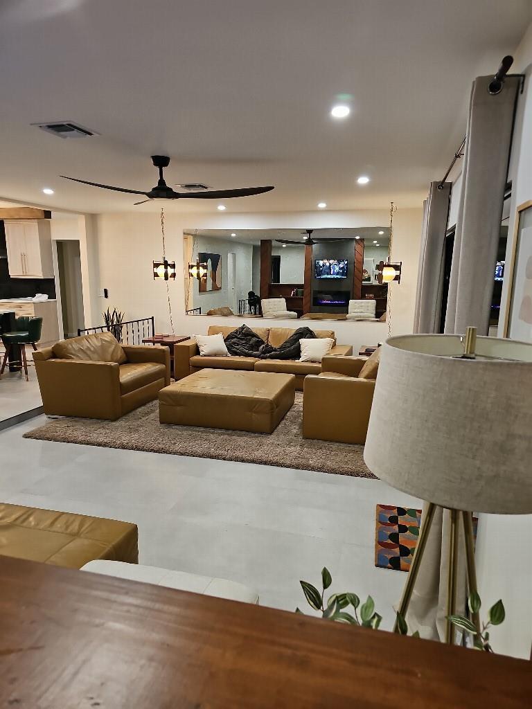 A living room features tan leather furniture, a large area rug, and a wall-mounted mirror — 7676 Overlook Drive, Lake Worth FL 33467, LAKE WORTH, FL