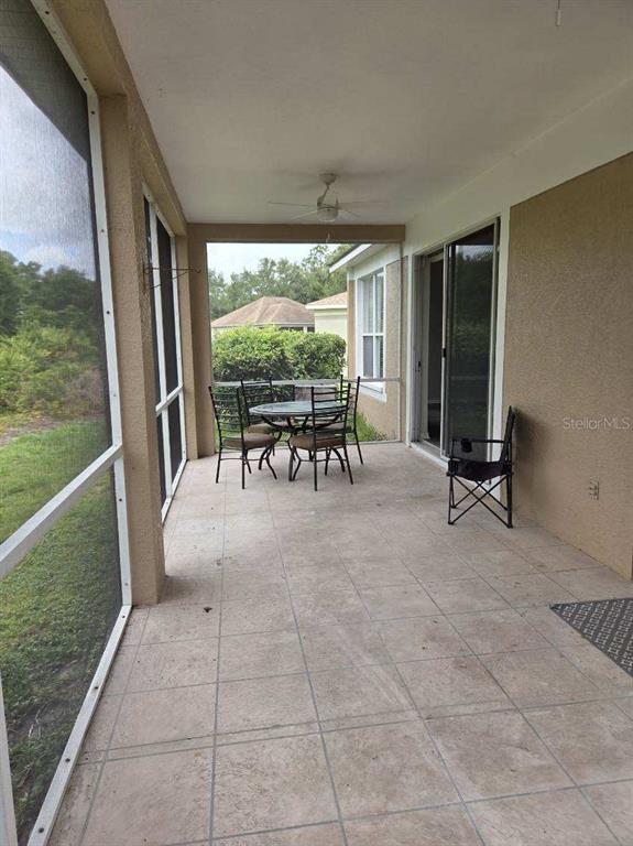 A screened-in patio features tiled flooring, a ceiling fan, and a small outdoor dining set — 9321 HUNTINGTON PARKWAY, TAMPA, FL
