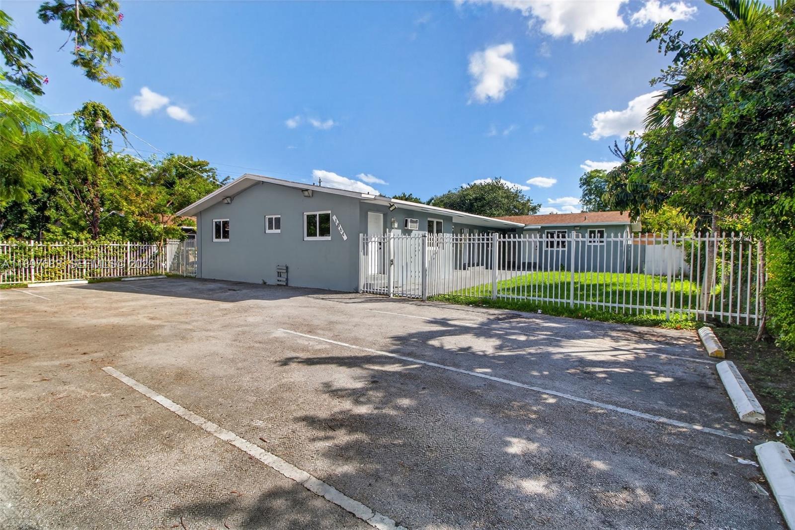 A gray single-story building with a parking lot and a white metal fence — 1864 NW 28th St, Miami FL 33142, MIAMI, FL