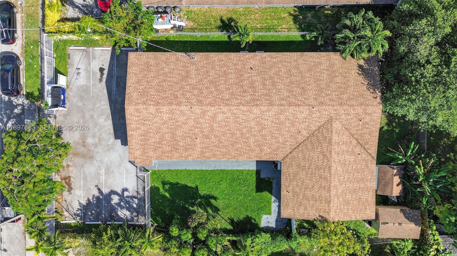 An aerial view shows a house with a brown shingled roof, parking lot, and yard — 1864 NW 28th St, Miami FL 33142, MIAMI, FL