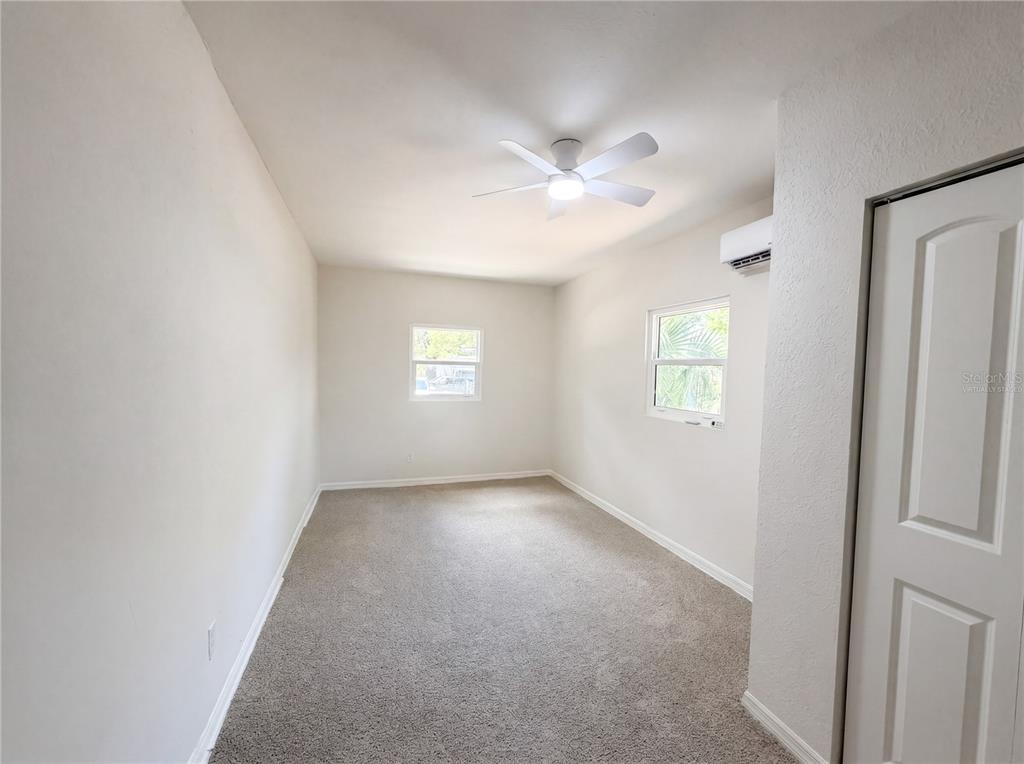 An empty bedroom features beige carpet, white walls, a ceiling fan, and two windows — 4010 E PARIS STREET, TAMPA, FL