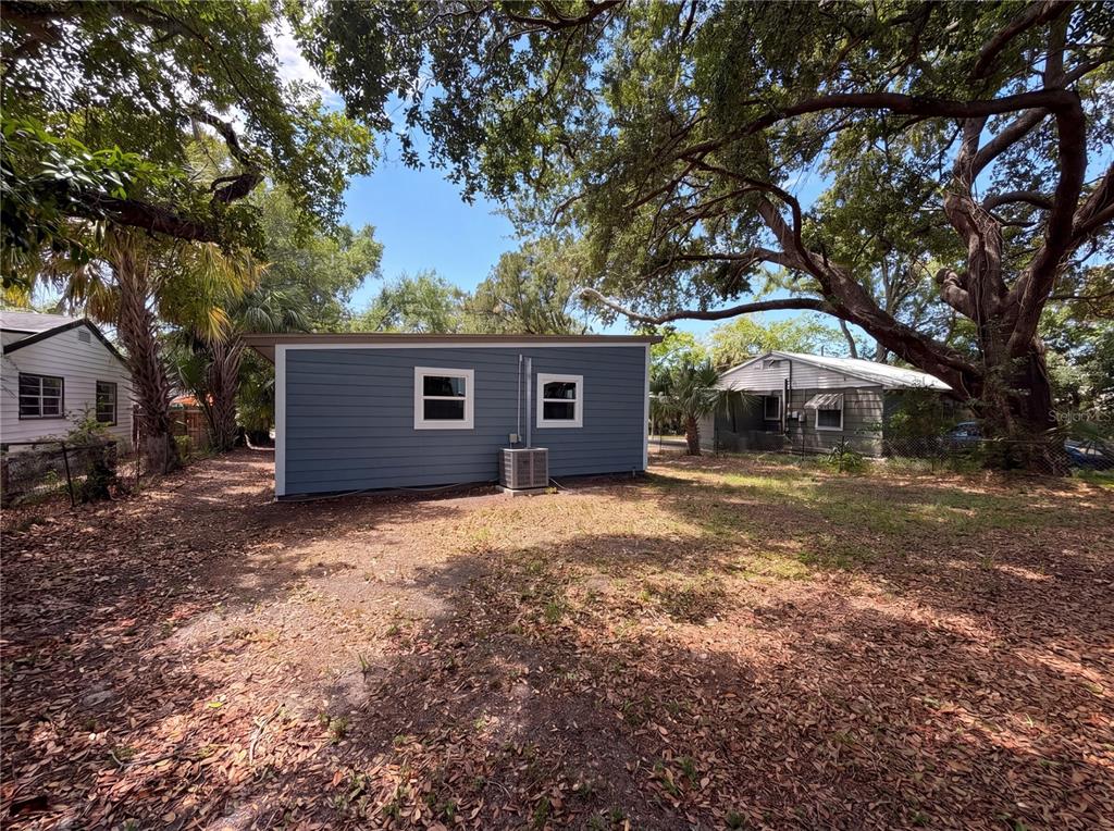 A blue-sided detached building stands in a yard with mature trees and neighboring houses — 4010 E PARIS STREET, TAMPA, FL
