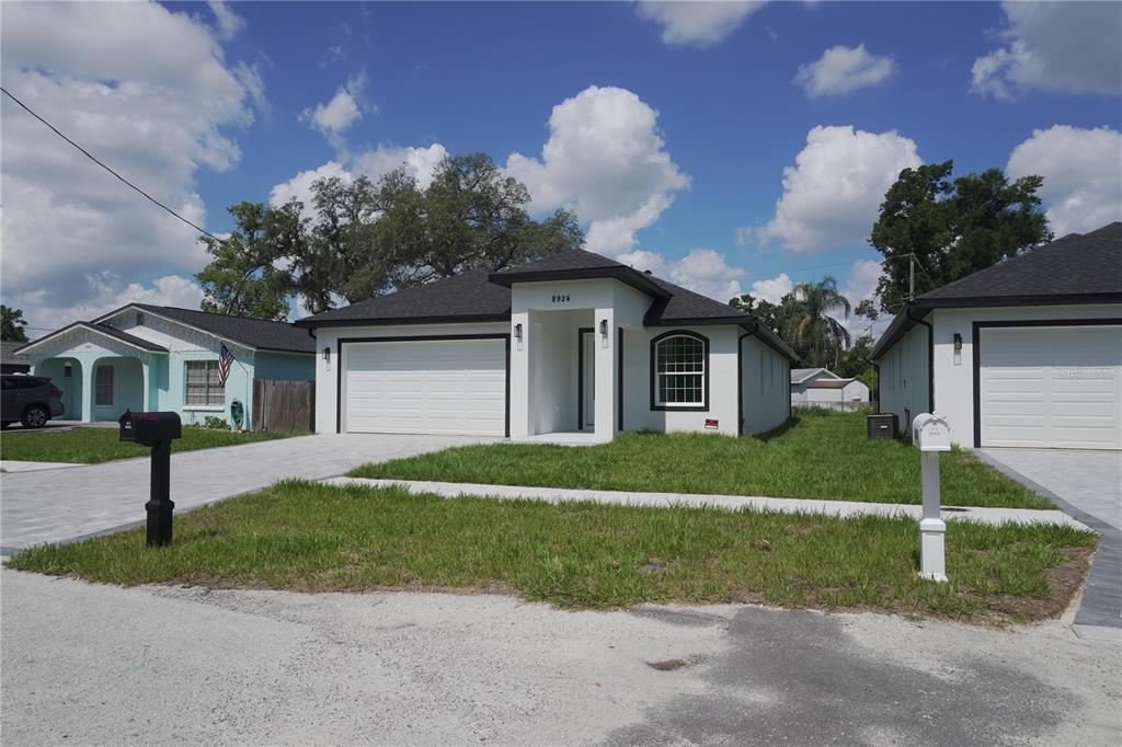 A single-story house with a white stucco exterior, a two-car garage, and a paved driveway — 8924 N ORLEANS AVENUE, TAMPA, FL