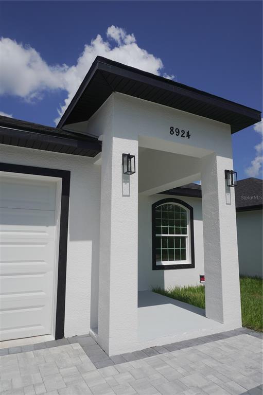 The exterior of a white house features a covered entryway, black trim, and a garage — 8924 N ORLEANS AVENUE, TAMPA, FL