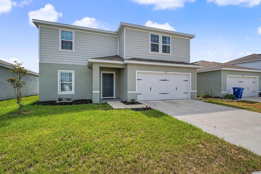 A two-story house with light-colored siding and stucco, a front door, and a two-car garage — 169 BORLAND STREET, BROOKSVILLE, FL