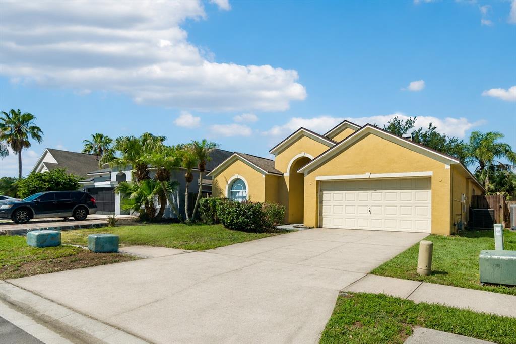 A yellow single-story house with a two-car garage and a concrete driveway — 1229 CRIMSON CLOVER LANE, WESLEY CHAPEL, FL