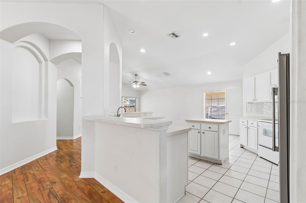 A kitchen with white cabinets, a center island, and tile flooring, adjacent to a hallway — 1229 CRIMSON CLOVER LANE, WESLEY CHAPEL, FL