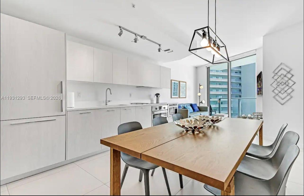 A modern kitchen and dining area with light wood cabinets, a wooden table, and balcony — 501 NE 31st St # 1607, Miami FL 33137, MIAMI, FL