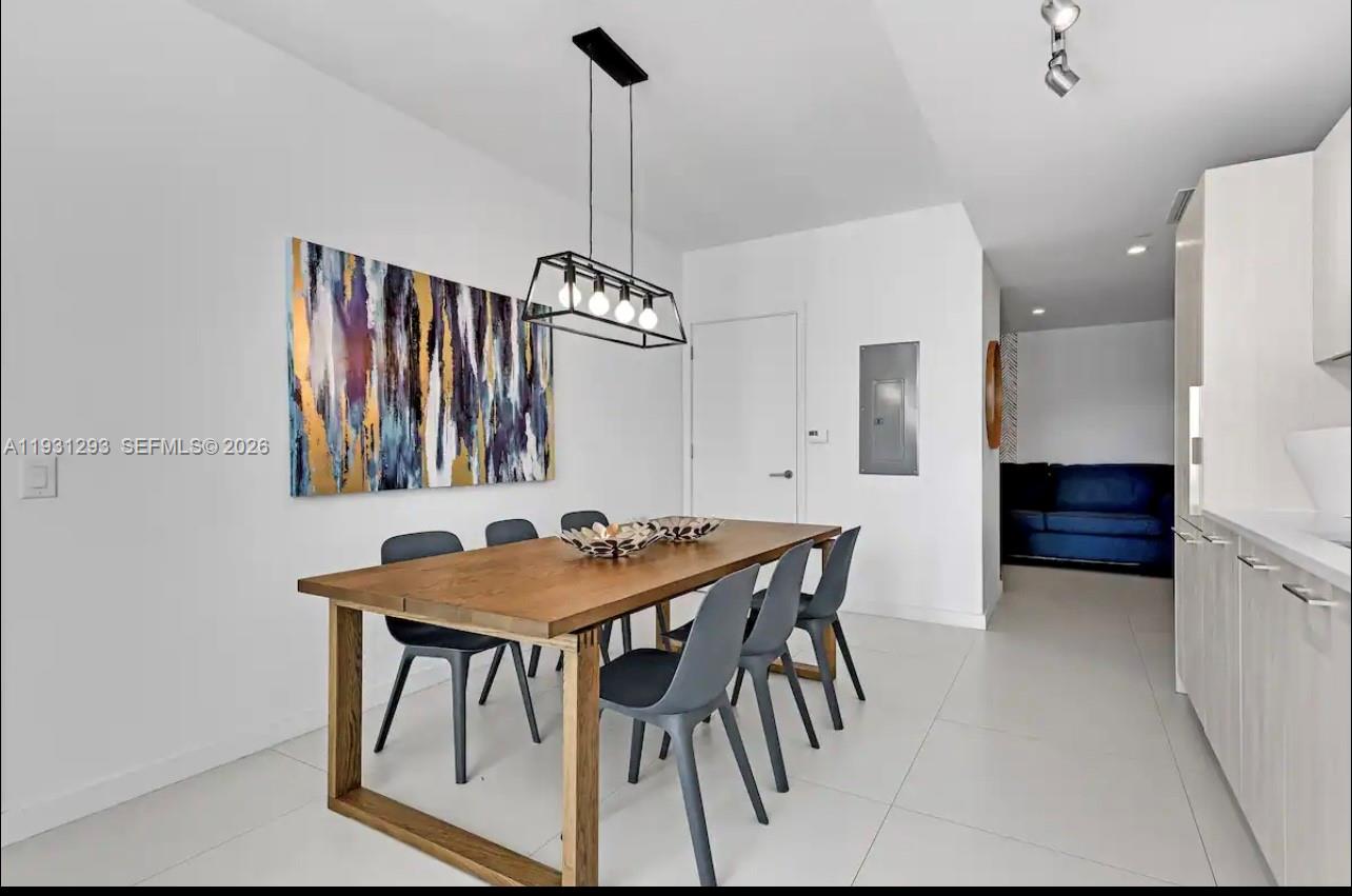 A dining area features a wooden table, grey chairs, and a modern rectangular pendant light — 501 NE 31st St # 1607, Miami FL 33137, MIAMI, FL