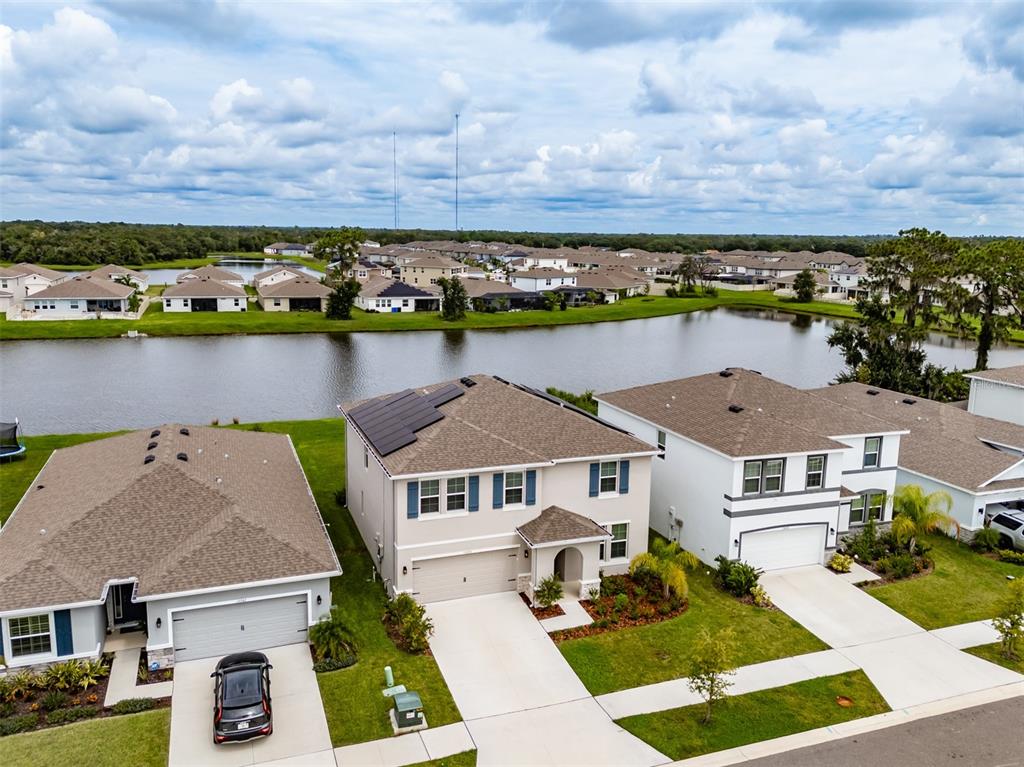 An aerial view shows three suburban houses with driveways situated along a lake — 13090 BROOKSIDE MOSS DRIVE, RIVERVIEW, FL