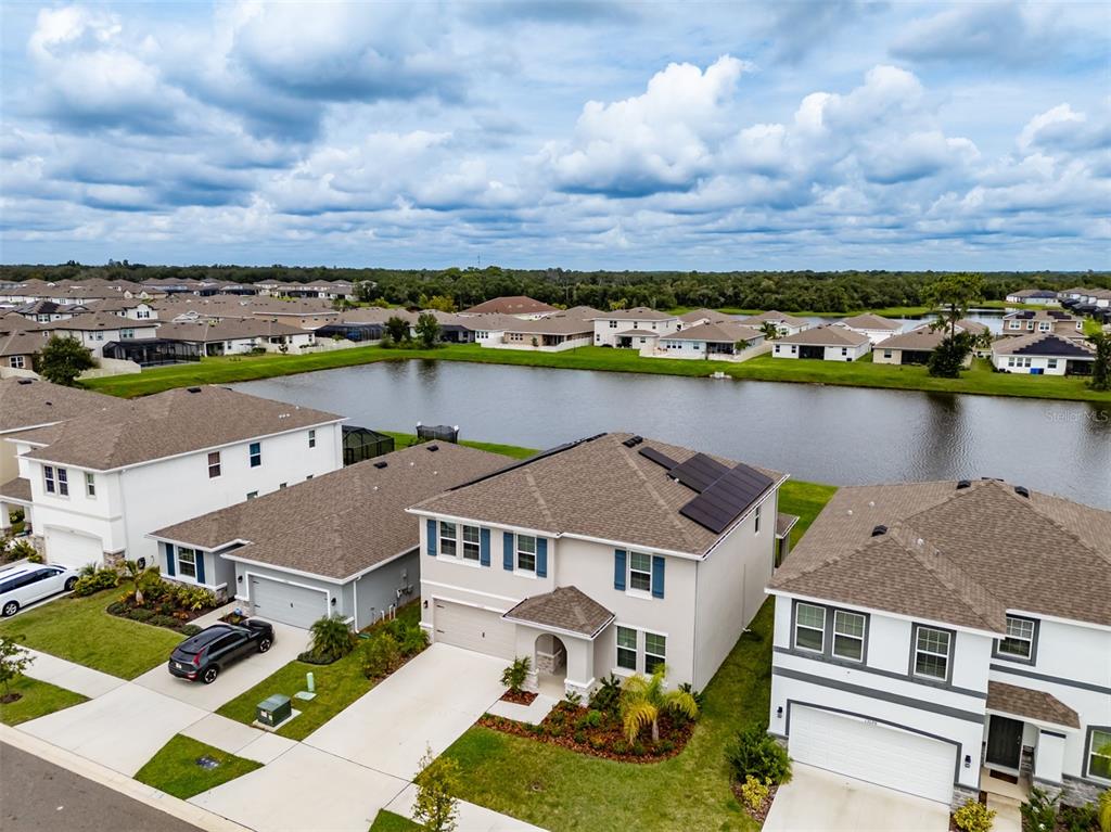 An aerial view shows several suburban houses with attached garages situated near a large pond — 13090 BROOKSIDE MOSS DRIVE, RIVERVIEW, FL