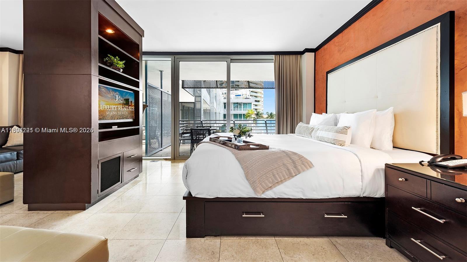A bedroom features a platform bed, dark wood furniture, tile flooring, and a balcony view — 1437 Collins Ave # 327, Miami Beach FL 33139, MIAMI BEACH, FL