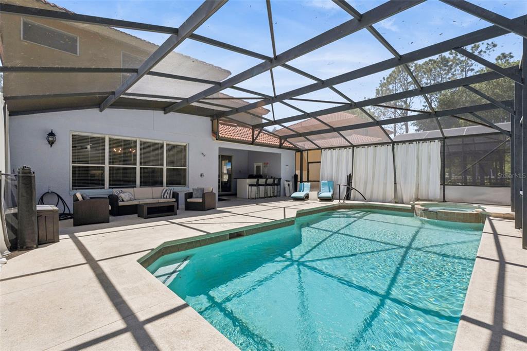 A screened-in patio features a swimming pool, a hot tub, and outdoor lounge furniture — 110 ORANGE COSMOS BOULEVARD, DAVENPORT, FL