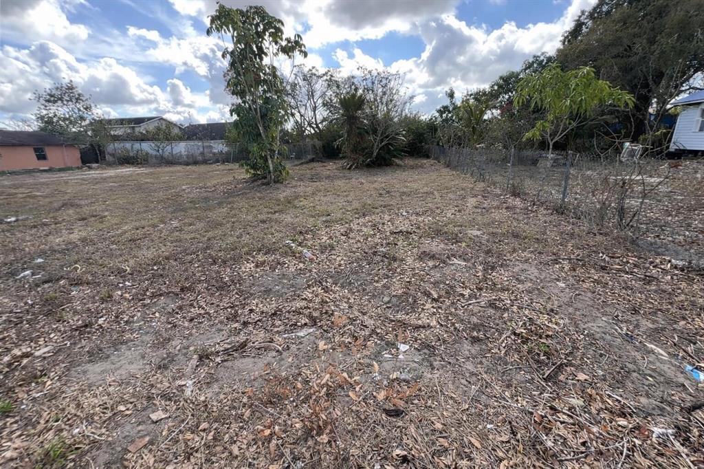 A vacant, grassy lot features scattered dry leaves, a few trees, and a chain-link fence — 841 BOOKER AVENUE, SEBRING, FL