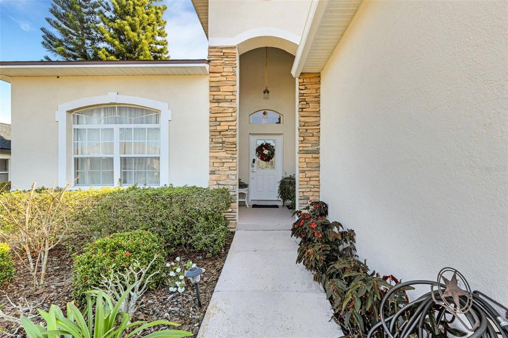 A concrete walkway leads to the front door of a house with stone accents — 2617 HICKORY VIEW LOOP, LAKELAND, FL