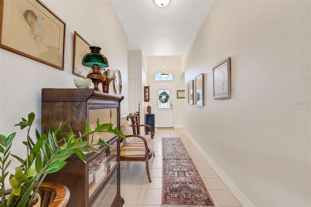 A tiled entryway features a wooden display cabinet, a bench, and a long patterned rug — 2617 HICKORY VIEW LOOP, LAKELAND, FL