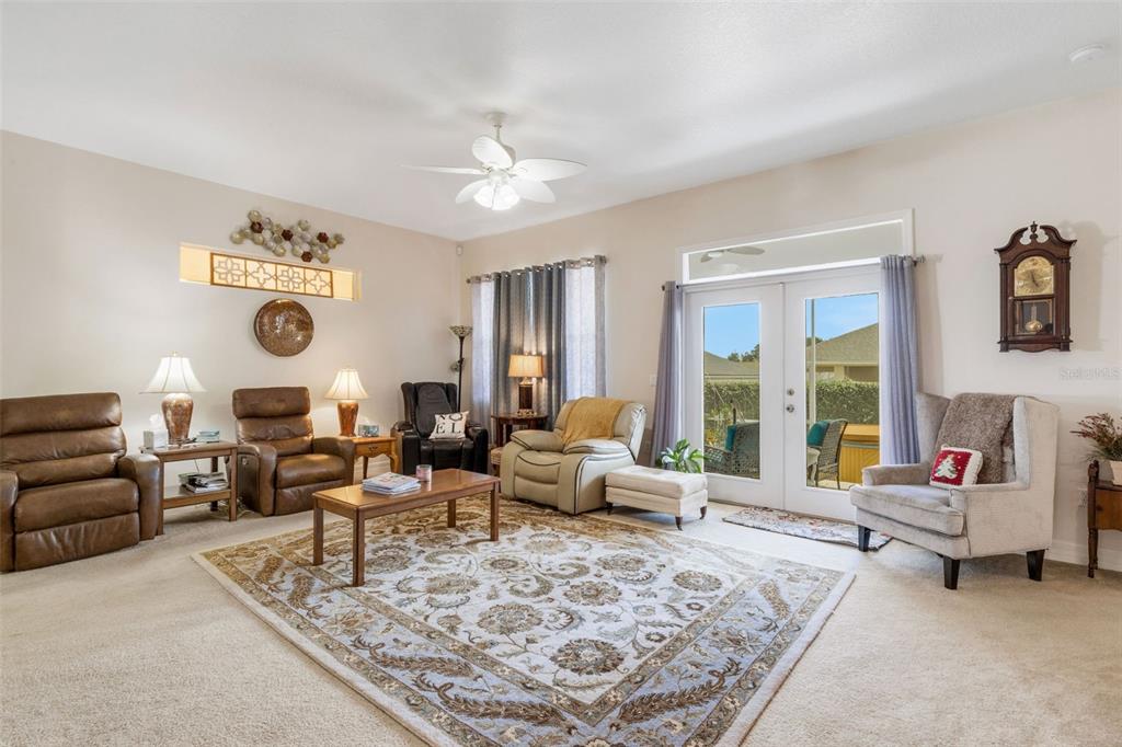 A living room features a large patterned area rug, multiple armchairs, and glass patio doors — 2617 HICKORY VIEW LOOP, LAKELAND, FL