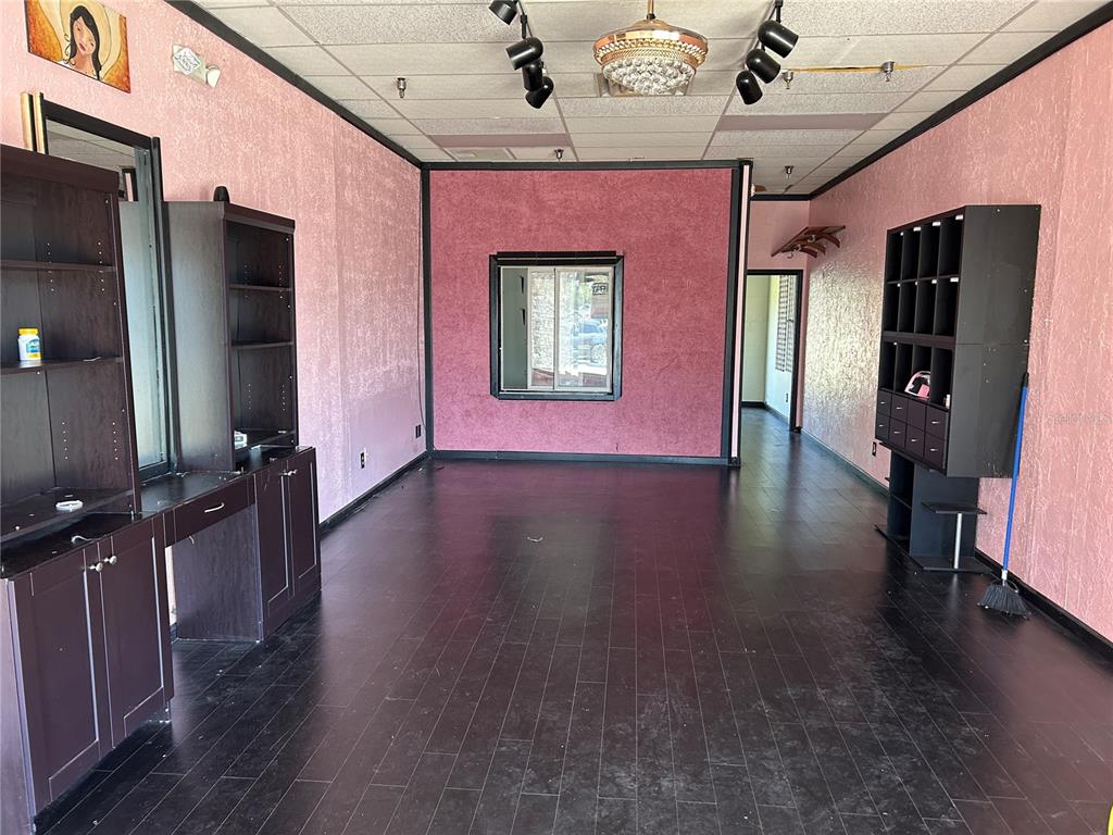An empty commercial space features pink textured walls, dark wood flooring, and black shelving units — 2400 SW COLLEGE ROAD UNIT 104, OCALA, FL