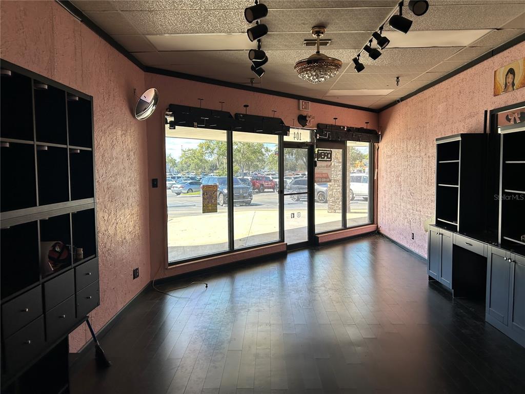 A commercial space features pink textured walls, dark wood flooring, and large storefront windows — 2400 SW COLLEGE ROAD UNIT 104, OCALA, FL