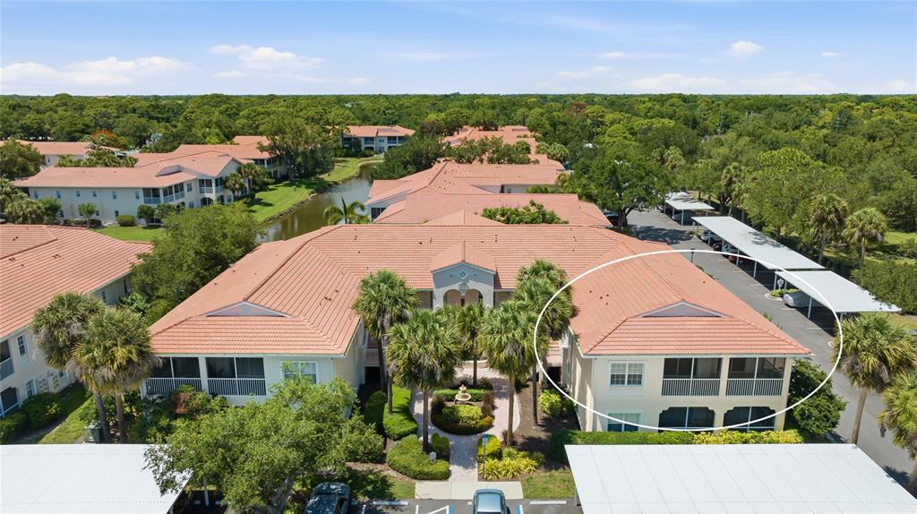 An aerial view shows a multi-story apartment building with a tiled roof and surrounding landscaping — 4244 CENTRAL SARASOTA PARKWAY UNIT 726, SARASOTA, FL