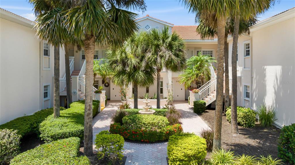 A courtyard with a fountain, palm trees, and landscaping sits between two residential building wings — 4244 CENTRAL SARASOTA PARKWAY UNIT 726, SARASOTA, FL