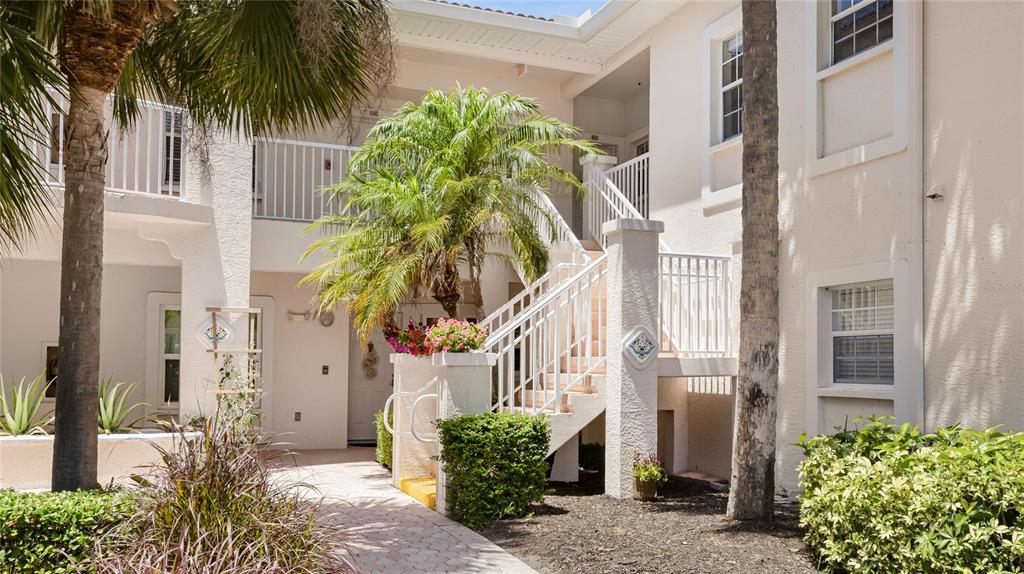 An exterior view of a multi-story apartment building with a staircase and palm trees — 4244 CENTRAL SARASOTA PARKWAY UNIT 726, SARASOTA, FL