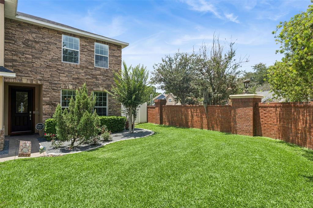 A two-story stone house with a front lawn and a brick perimeter wall — 2708 PEPPER LANE, ORLANDO, FL