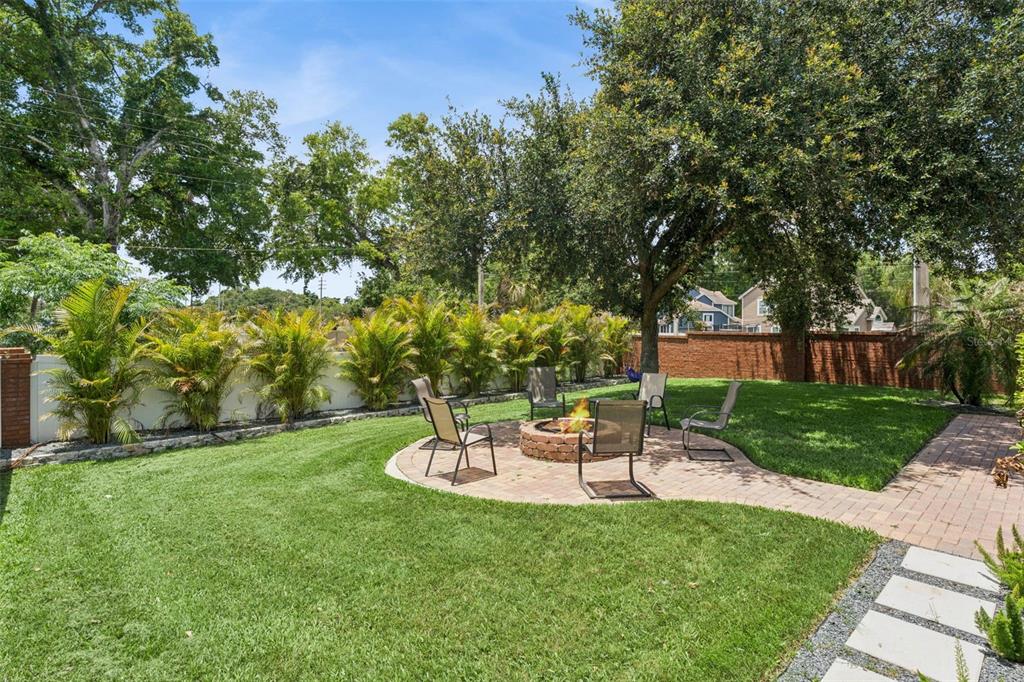 A backyard features a circular brick patio with a fire pit and several outdoor chairs — 2708 PEPPER LANE, ORLANDO, FL