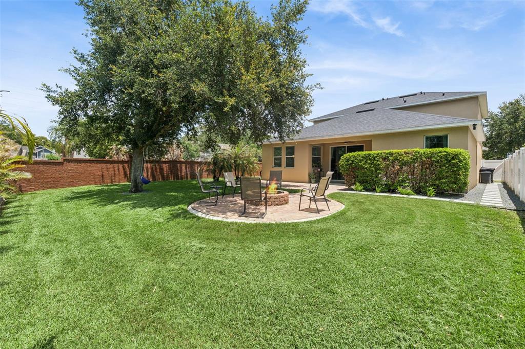 A backyard features a circular paver patio with a fire pit and outdoor seating — 2708 PEPPER LANE, ORLANDO, FL
