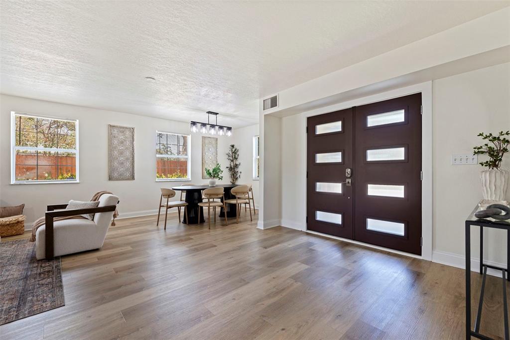 A bright dining and living area features light wood flooring and a dark double door — 1470 28TH AVENUE N, ST PETERSBURG, FL