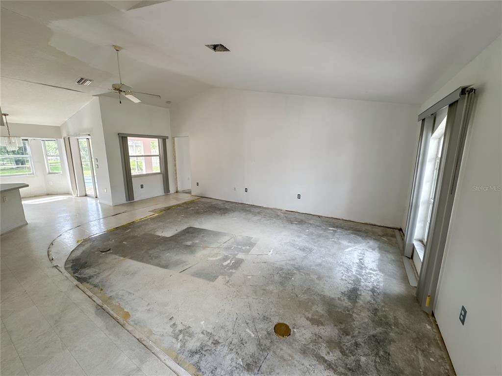An unfinished living room with a concrete subfloor, vaulted ceilings, and large windows — 5431 S CRANBERRY BOULEVARD, NORTH PORT, FL