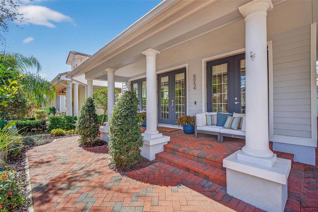 A front porch with a brick walkway, white columns, and a gray double door entrance — 6054 YEATS MANOR DRIVE, TAMPA, FL