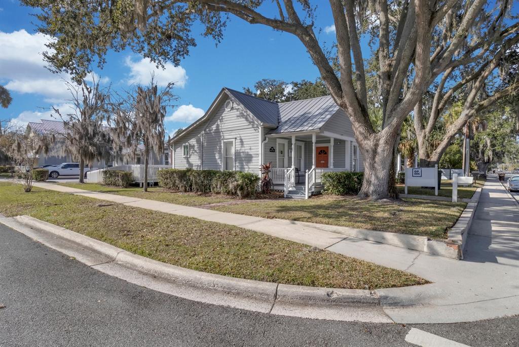 A light gray house with a metal roof and an orange front door sits on a corner — 802 MABBETTE ST, KISSIMMEE, FL
