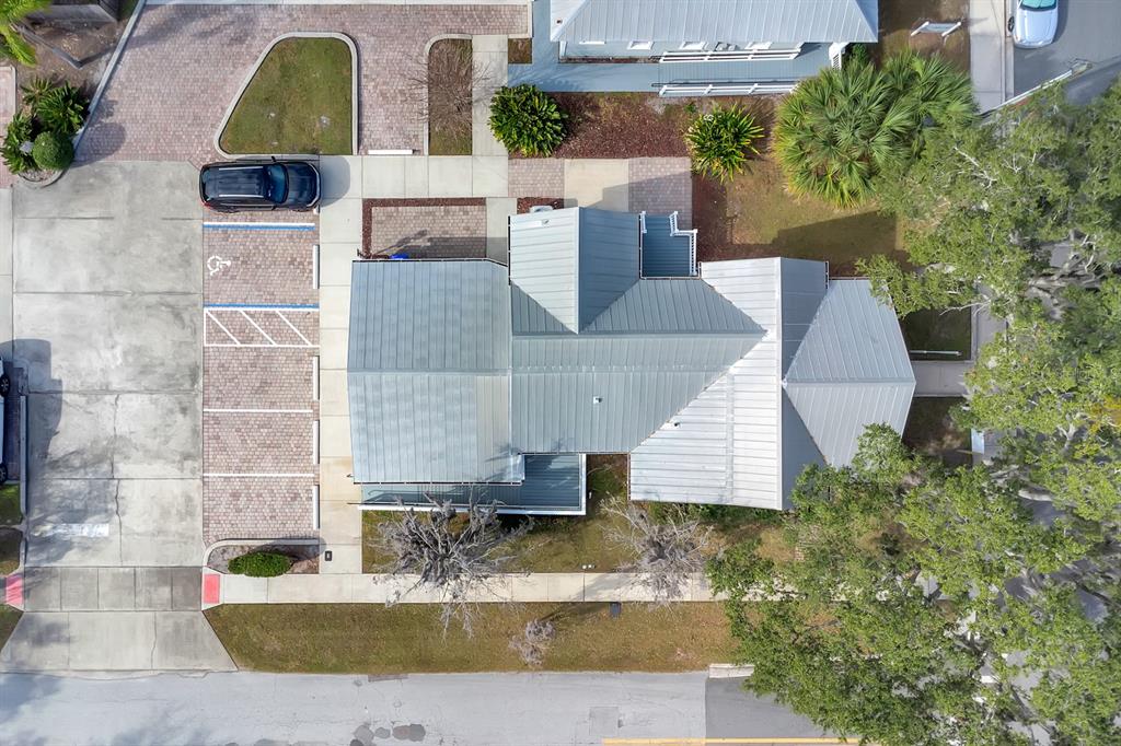 An aerial view shows a building with a metal roof, parking spaces, and surrounding landscaping — 802 MABBETTE ST, KISSIMMEE, FL