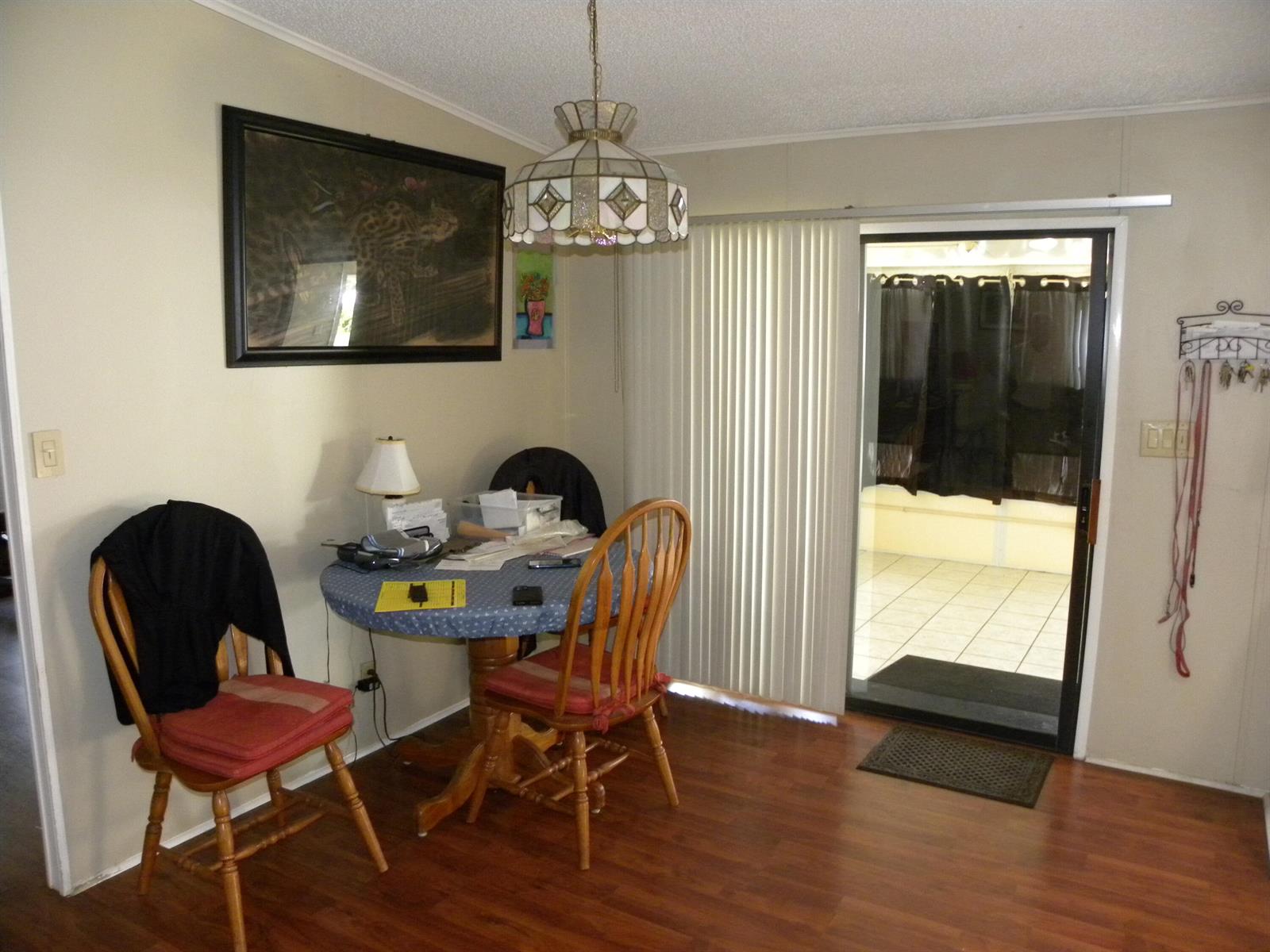 A dining area features a round table, two wooden chairs, a pendant light, and sliding doors — 456 Tropical Isles Circle, Fort Pierce FL 34982, FORT PIERCE, FL