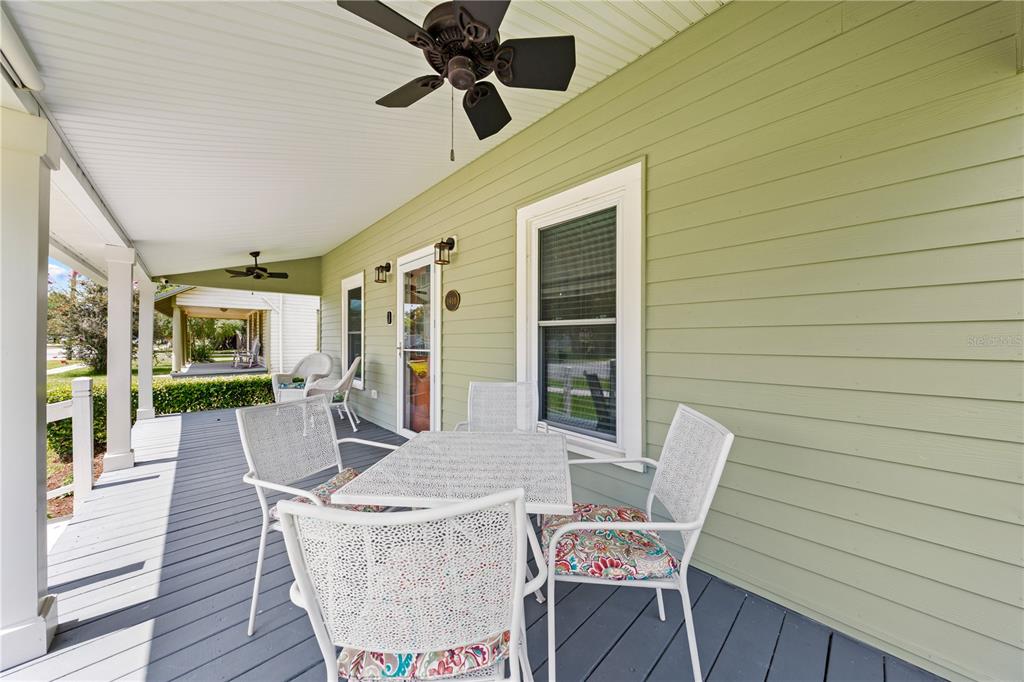 A covered porch features light green siding, a ceiling fan, and a patio dining set — 714 MASSACHUSETTS AVENUE, ST CLOUD, FL